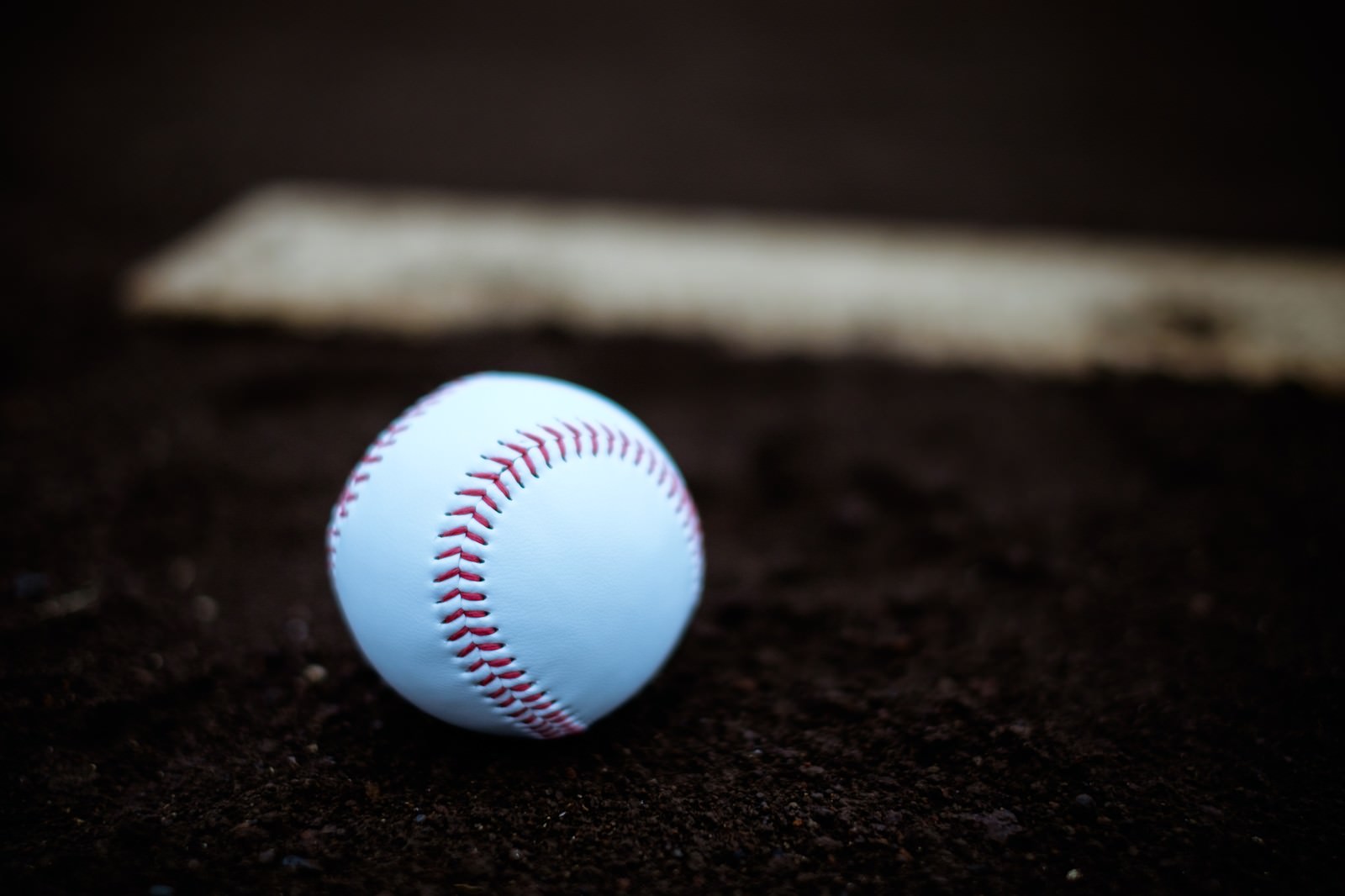野球のプレート横に置かれた赤いステッチの硬球