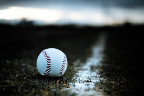 ラインギリギリに転がるベースボール、白い硬球と赤い縫い目