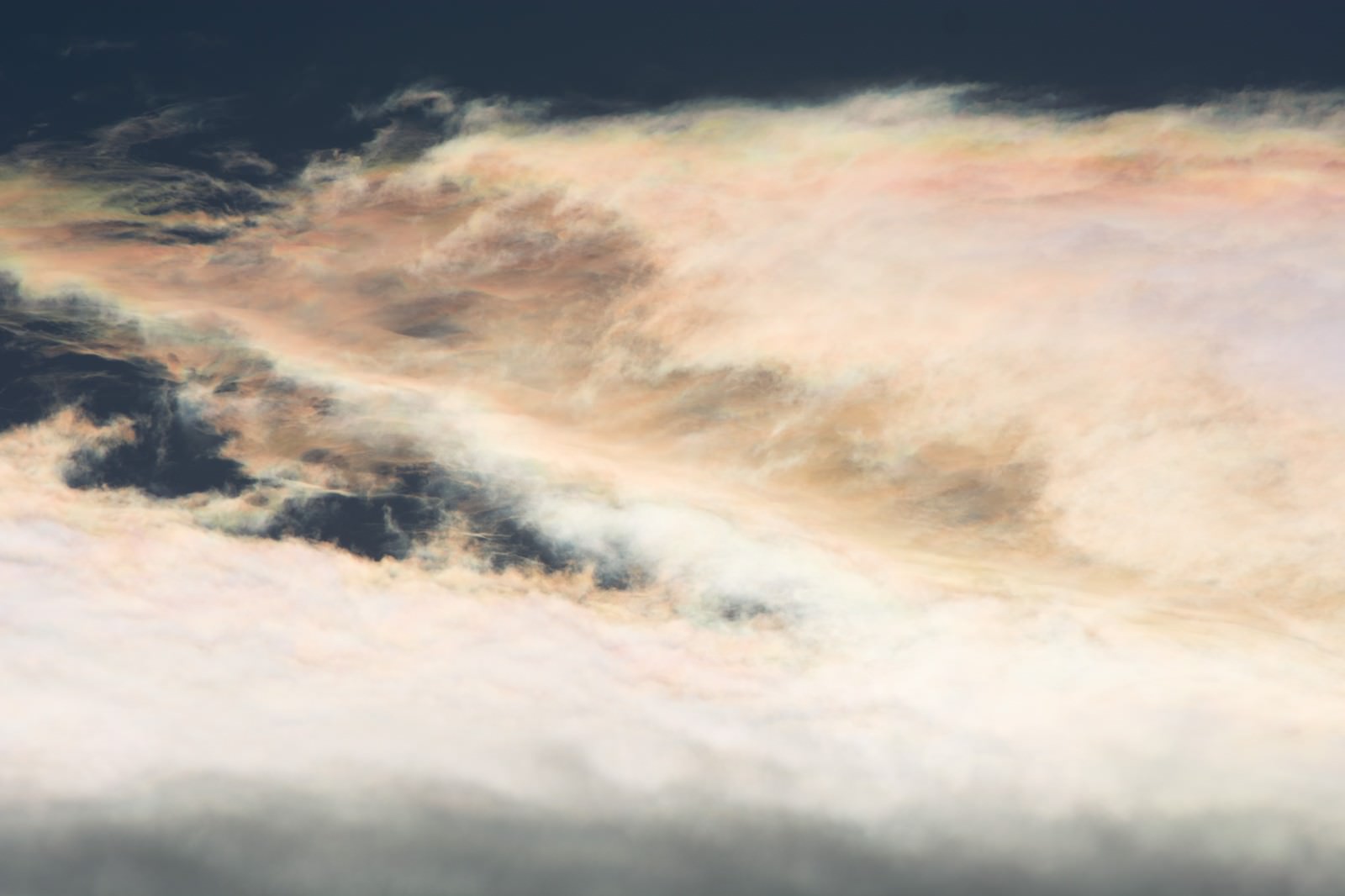 オレンジやピンクに染まる彩雲と暗い雲が重なる空
