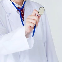 白衣を着て聴診器を患者の胸に当てて診察する医師の写真