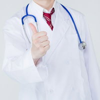 親指を立てて「グッジョブ！」のポーズをする笑顔の白衣の医師の写真