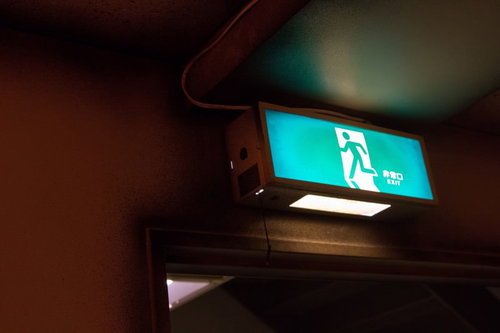 暗い廊下の天井でぼんやりと光る薄暗い非常灯