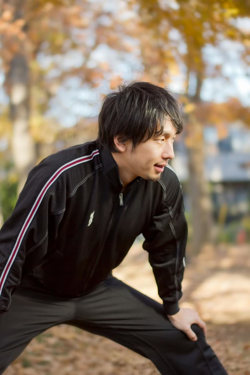 ストレッチの準備運動をするジャージの男性［モデル：大川竜弥］