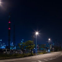 車のヘッドライトが連なる夜の工業地帯の幹線道路の写真