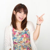 白い背景の前で笑顔で横を指差して「こちらをどうぞ」と案内する女性の写真