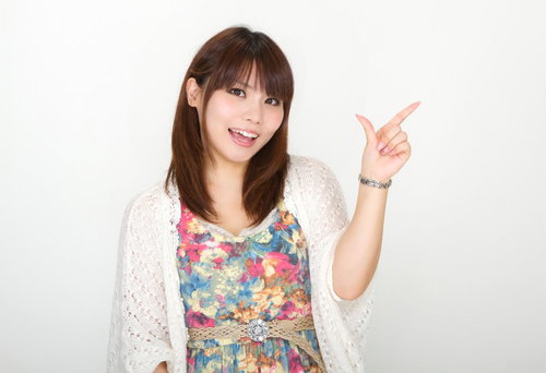 白い背景の前で笑顔で横を指差して「こちらをどうぞ」と案内する女性