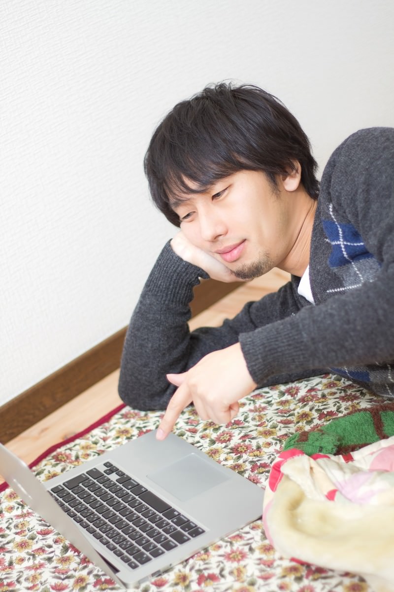モニターを指して薄ら笑いの男性［モデル：大川竜弥］