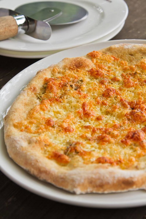 ピザカッターの丸い刃が添えられた焼きたてピザの接写