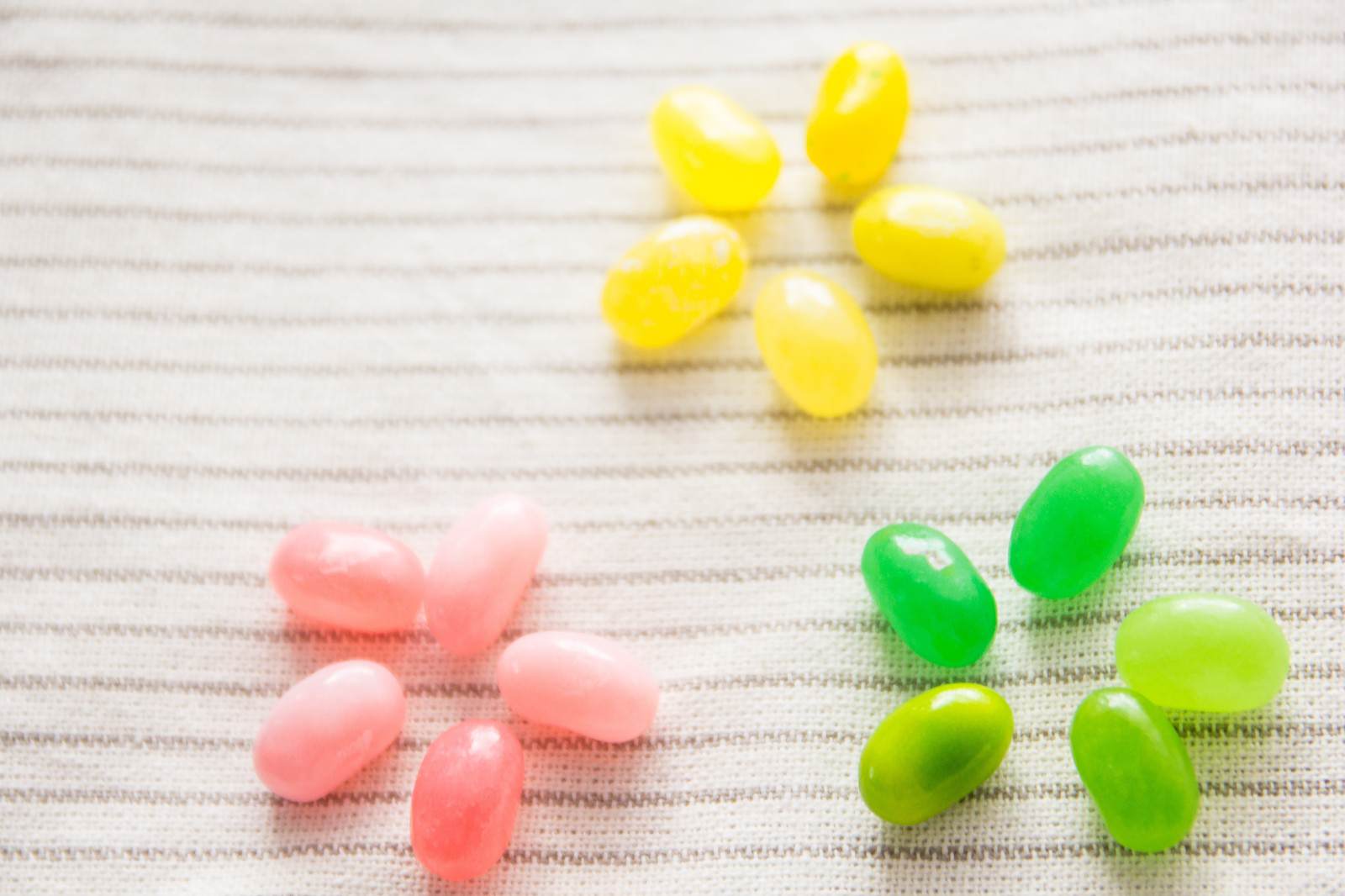 黄色、ピンク、緑のジェリービーンズが花の形に配置された菓子素材