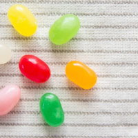 白い布の上に並ぶカラフルなゼリービーンズ7個の写真