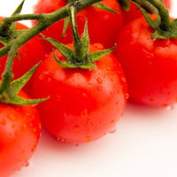 水滴が付いた緑のヘタ付きの赤いトマト3個の写真