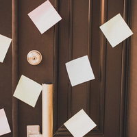 縦溝模様の茶色い木製ドアに複数の白い付箋と金色の鍵穴が写る接写の写真