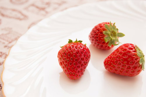 白い皿にイチゴ3つとピンクの花柄の布