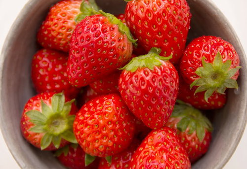 茶色の器にぎっしり詰まった赤いいちご