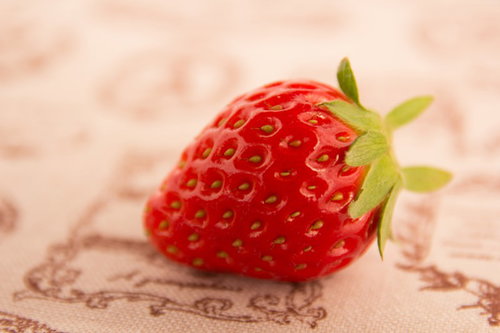 ベージュの布に置いた赤い一粒のイチゴ