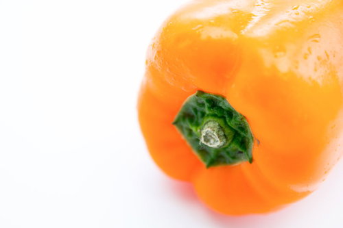 白い背景に置かれた黄色いパプリカ、緑のヘタ付き