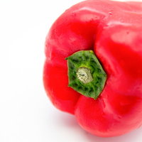 緑のヘタが付いた赤いパプリカ、白背景での撮影の写真
