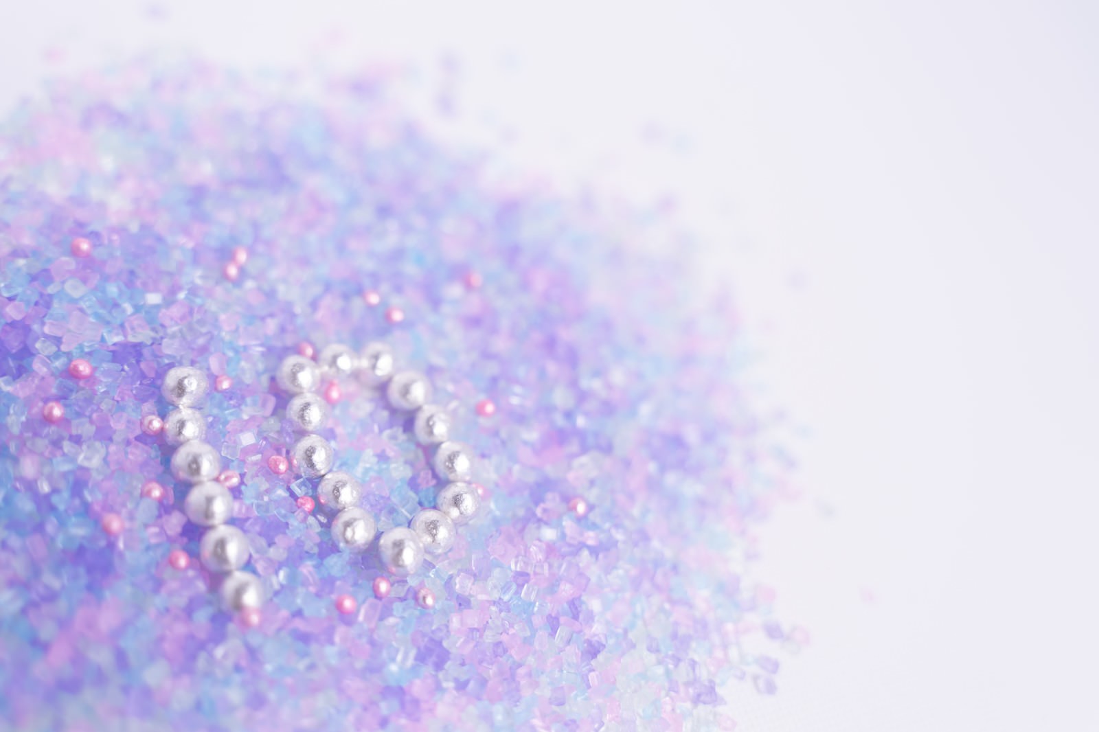 白いパールで形作った数字の10と、周囲に散らばるピンク、紫、青色のグリッターとビーズ