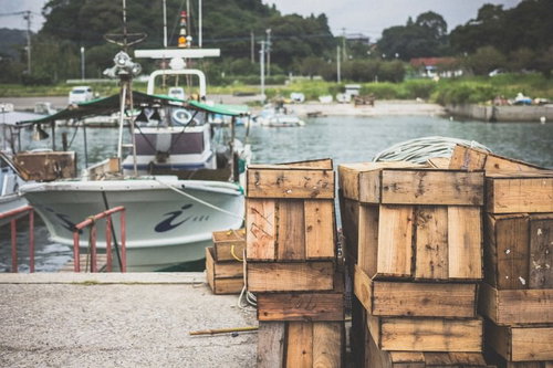 漁港に積み上げられた木製の漁具と漁船の風景