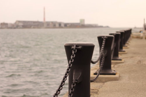 チェーンで繋がれた黒い係船柱が並ぶ港