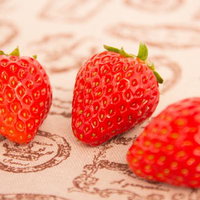 紙の上に置いた赤いイチゴ3個の写真