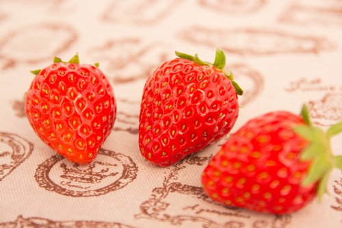 紙の上に置いた赤いイチゴ3個