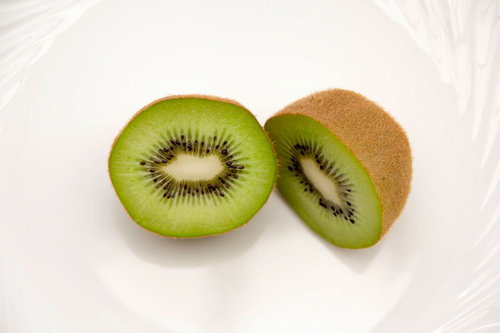 白い皿の上の輪切りと半分に切ったキウイフルーツ