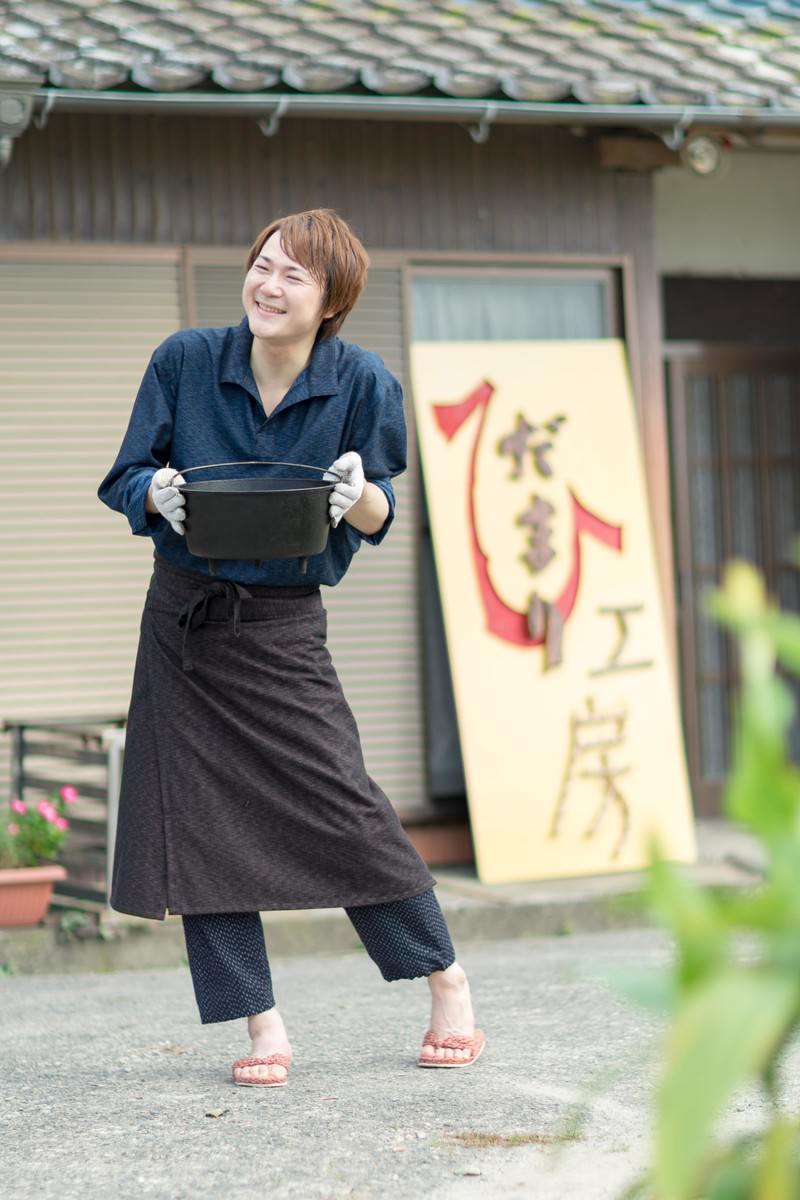 古民家の前でダッチオーブンを持つ女性［モデル：五十嵐夫妻］