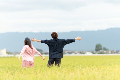広大な田園風景に溶け込むもんぺ姿の夫婦、秋の稲田で新しい暮らしを営む