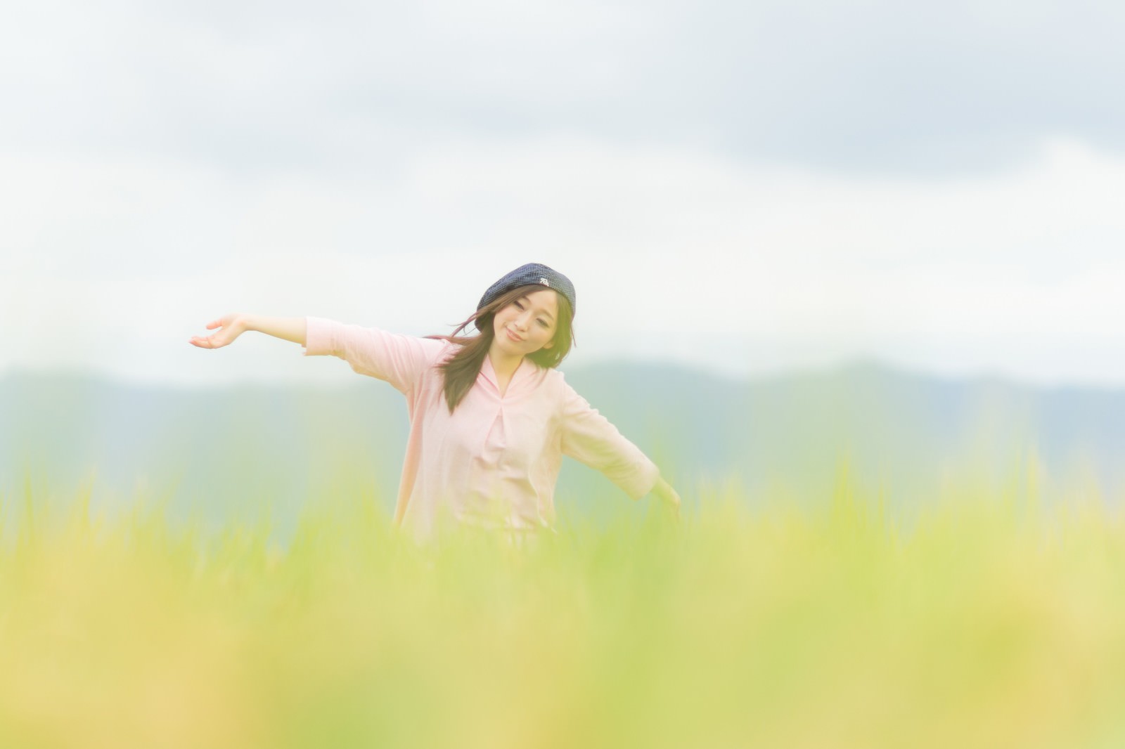 金色の稲穂の田んぼに立つもんぺ姿の女性［モデル：五十嵐夫妻］