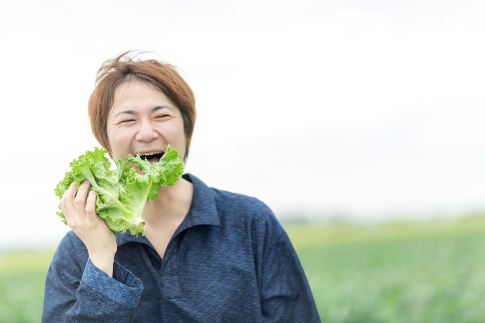大刀洗産のサニーレタスを頬張る笑顔の男性農夫［モデル：五十嵐夫妻］