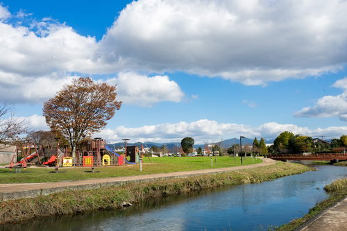 川沿いにある大刀洗公園の遊具広場と青空、春の景観