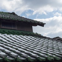 瓦屋根に雪が残る日本家屋の冬景色の写真