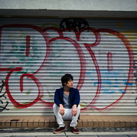 シャッター前に集合したのは僕だけでした。グラフィティの壁に座り込む男性の写真