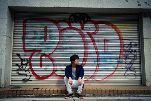 シャッター前に集合したのは僕だけでした。グラフィティの壁に座り込む男性