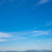 遠くの山が青く見えるほどの晴天の空と白い雲の写真