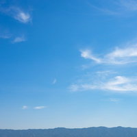 晴れた日に見える青空と白い雲、遠くの山並みの写真