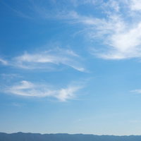 山沿いに一時的に晴れ渡った空と白い雲の写真