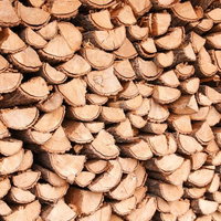 暖炉用に積み上げられた薪の断面と積み重ねられた丸太の写真