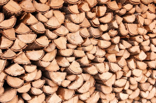 暖炉用に積み上げられた薪の断面と積み重ねられた丸太