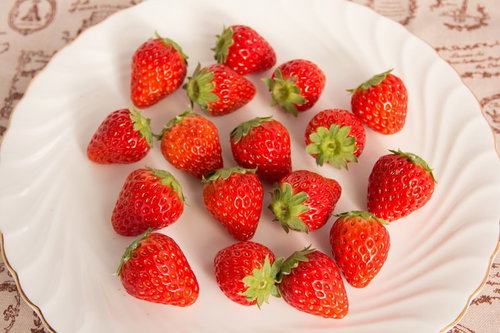 白いお皿の上に散らばった採れたての苺の食材の写真
