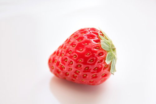 白い背景に置かれた新鮮な苺一粒の高品質写真の写真