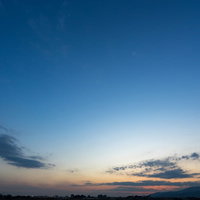 夕暮れ時、日が沈み青空がオレンジに染まる景色の写真