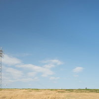 河川敷に立つ高圧送電鉄塔と青空の風景の写真