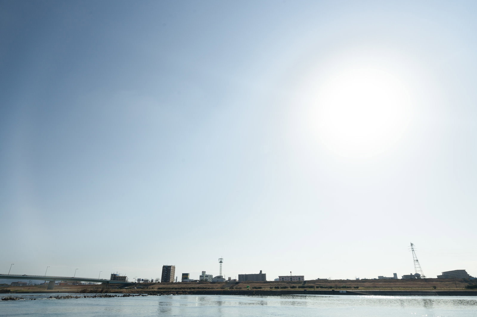 河川敷から見た工業地帯の鉄塔とビルの風景