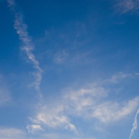 日が暮れてきた青空に放射状に伸びる飛行機雲の写真