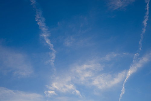 日が暮れてきた青空に放射状に伸びる飛行機雲
