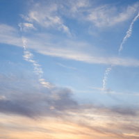 夕暮れと青空のグラデーション、飛行機雲が横切る空の写真