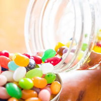 瓶から溢れだしたカラフルなジェリービーンズとキャンディの写真