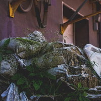 放置された土嚢と雑草が茂る工場跡地の風化した風景の写真